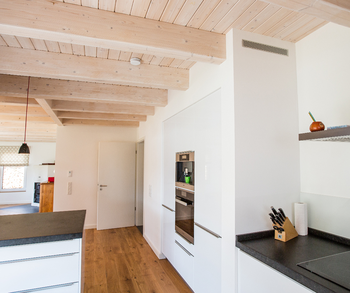 Weiße Küche im Neubau mit Parkettboden und Holzvertäfelung an der Decke